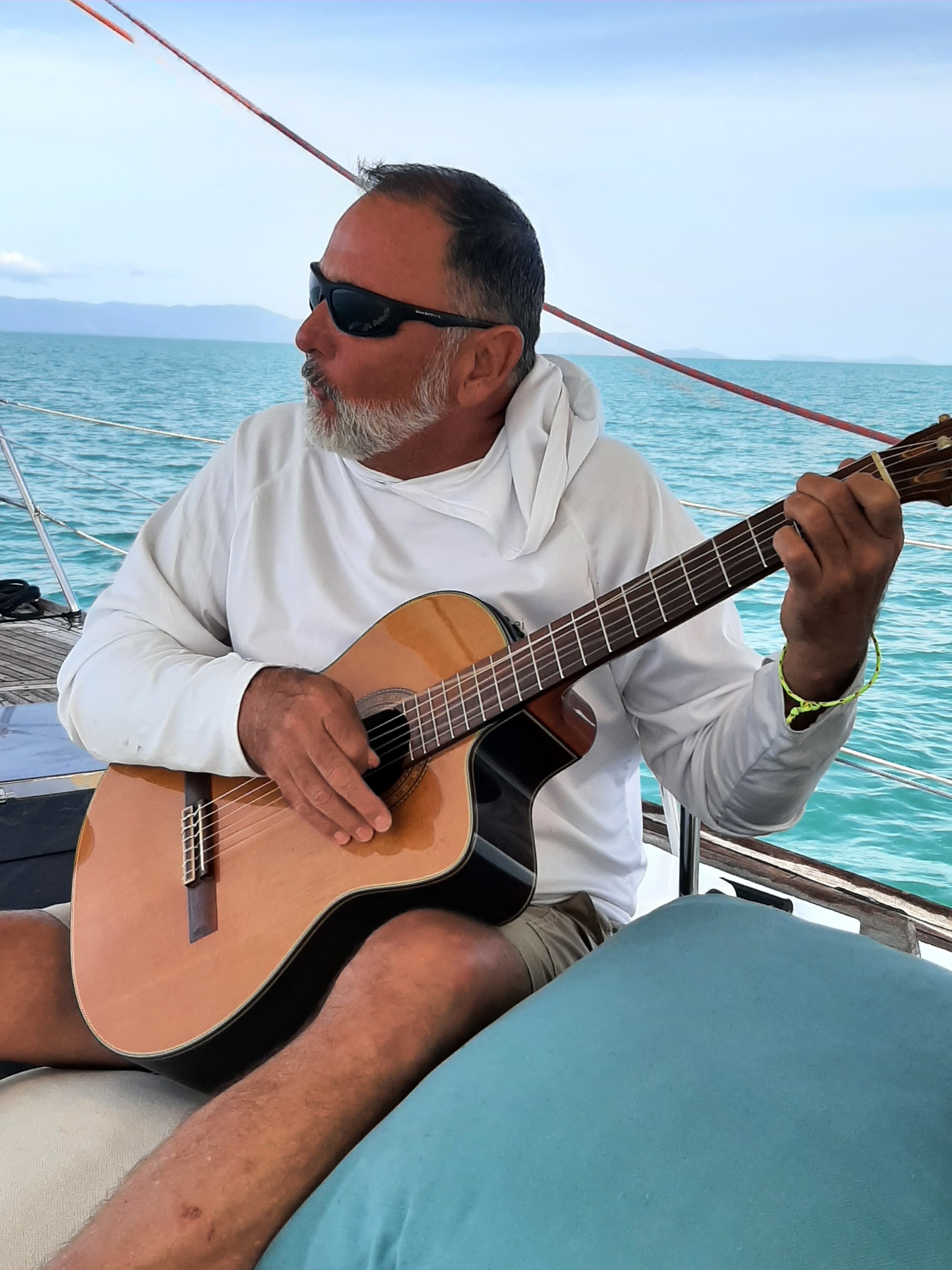 B. Douglas playing acoustic guitar on the water in Thailand